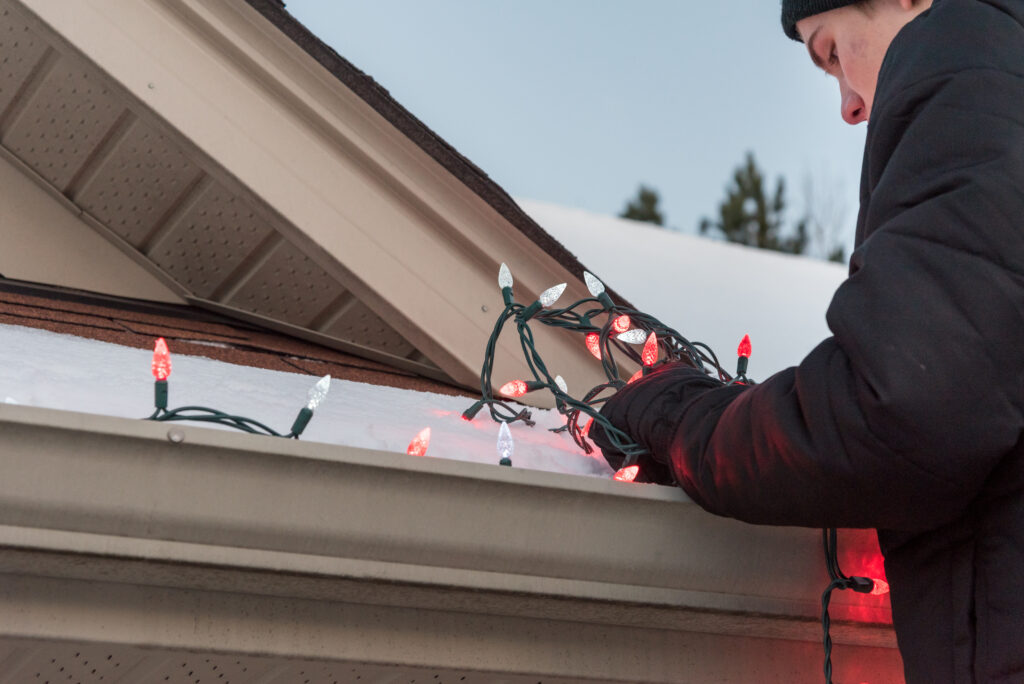 Man Standing on Ladder Hanging Festive Lights