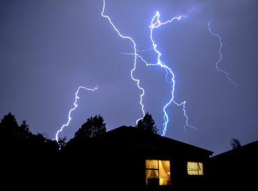 Large Lightning Bolts in Dark Sky Behind Home - K-Guard Heartland