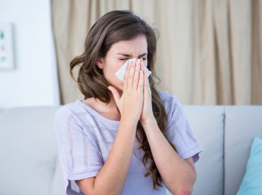 Woman Blowing her Nose Sitting on Couch - K-Guard Heartland