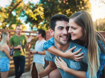Shot of a young couple enjoying a piggyback ride while hanging out with their friends.