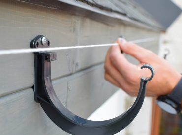 Man,Hands,Installing,Dark,Grey,Plastic,Roof,Gutter,Holder,On